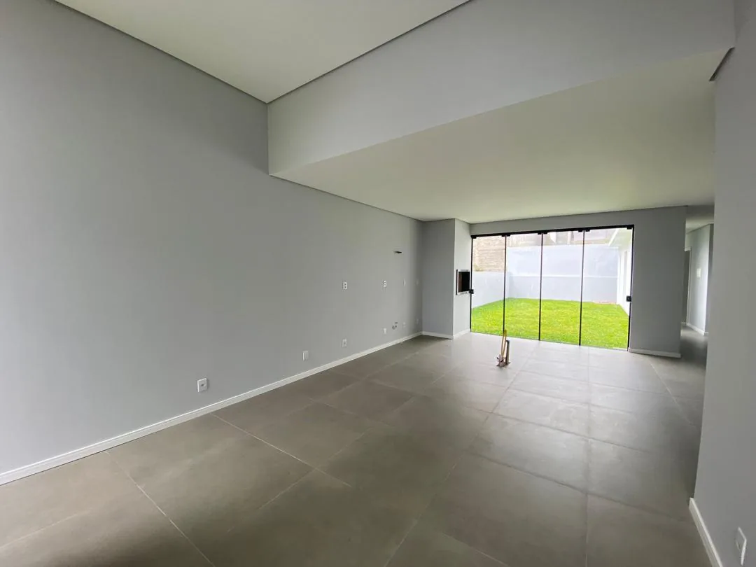 Living com rebaixo de gesso e portas de vidro que abrem para o pátio gramado dos fundos