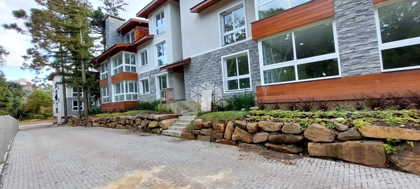 Fachada do residencial com muro de pedra e jardim