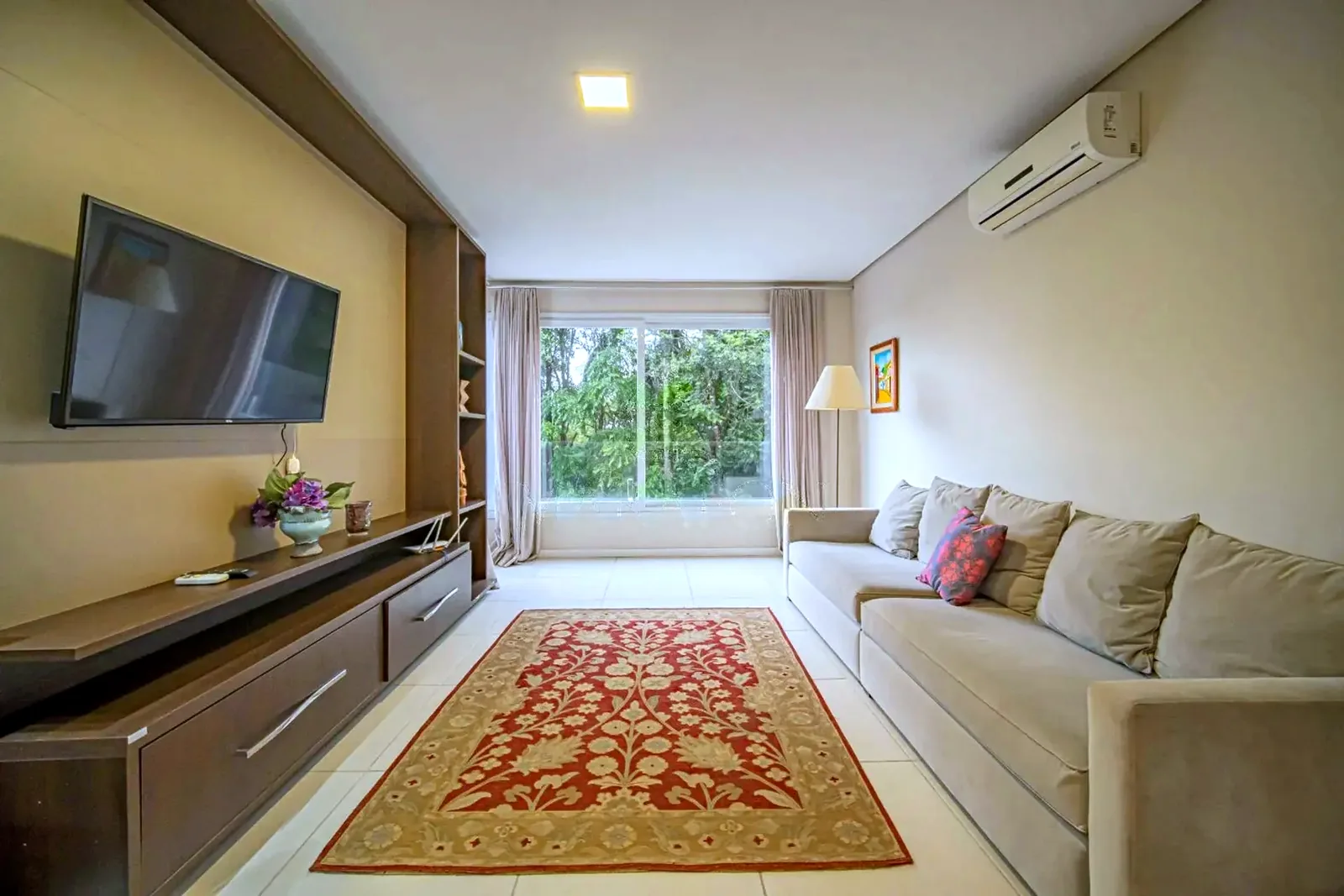 Sala de estar mobiliada com janelão para a mata