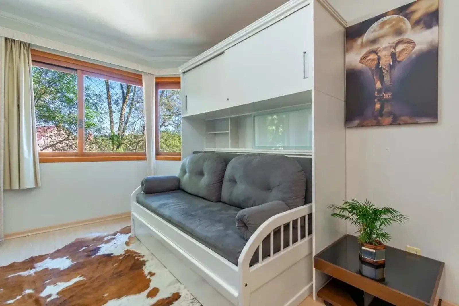 Sala de estar com sofá e janelas para o verde