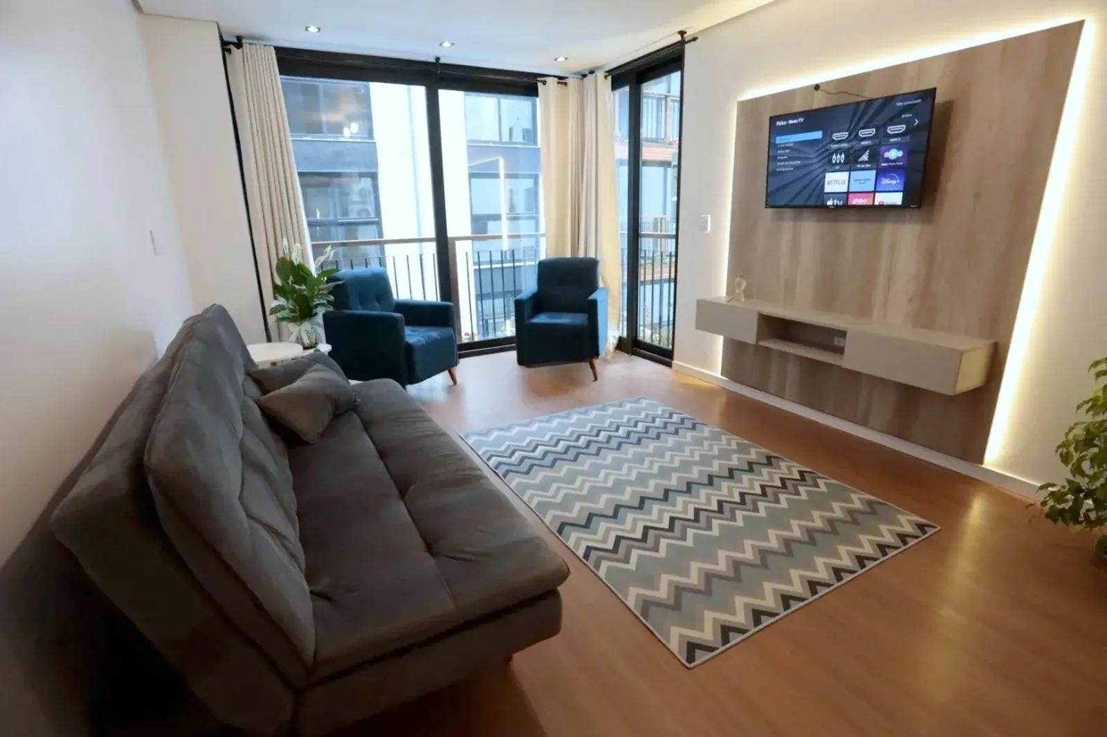 Living com sofá, TV e janelas amplas