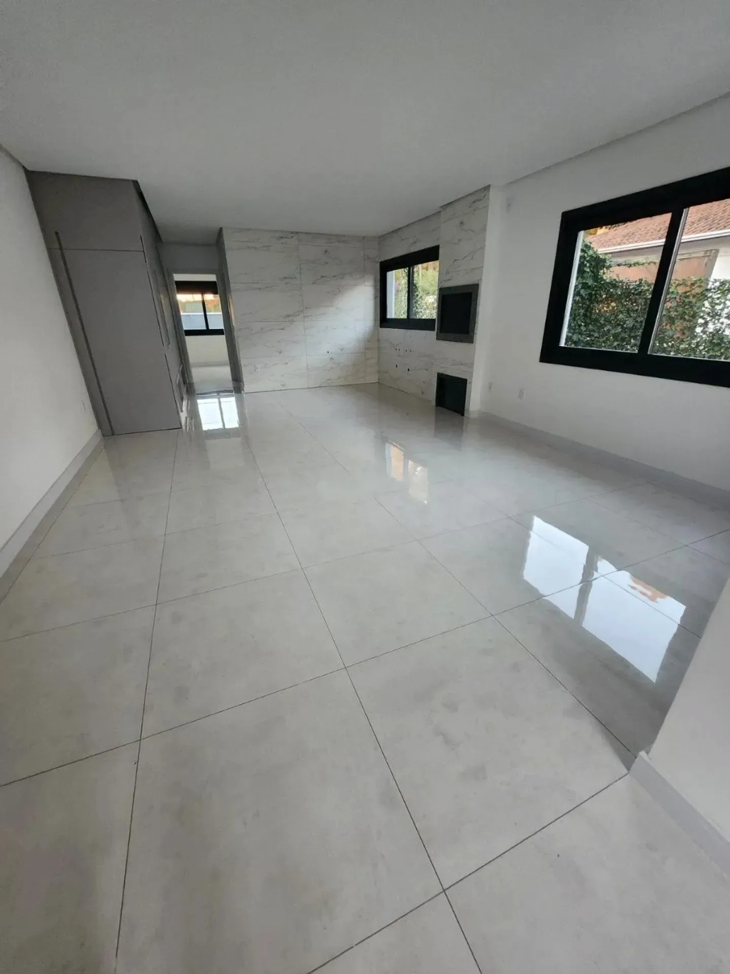 Sala ampla com porcelanato e janela para o jardim