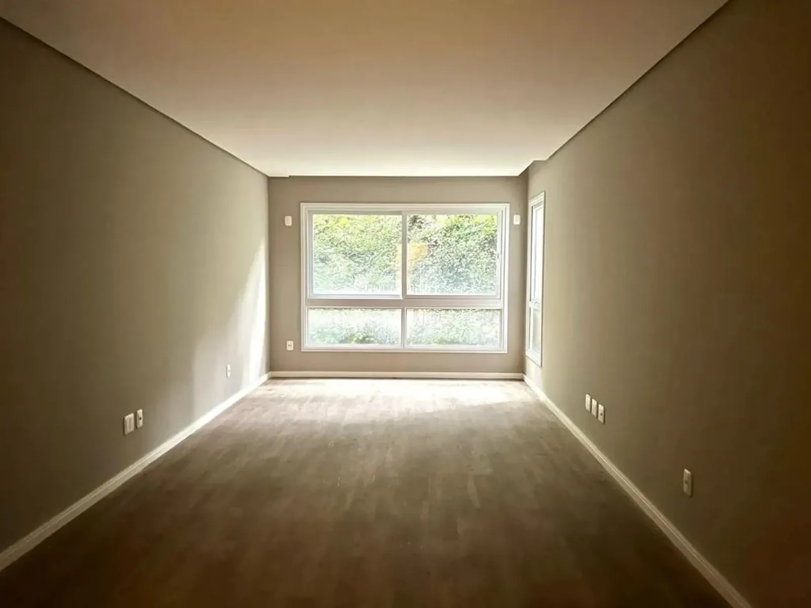 Sala vazia com janela ampla de quatro folhas voltada para a mata