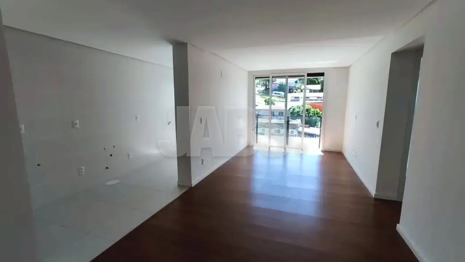 Sala ampla com piso laminado e vista para o verde