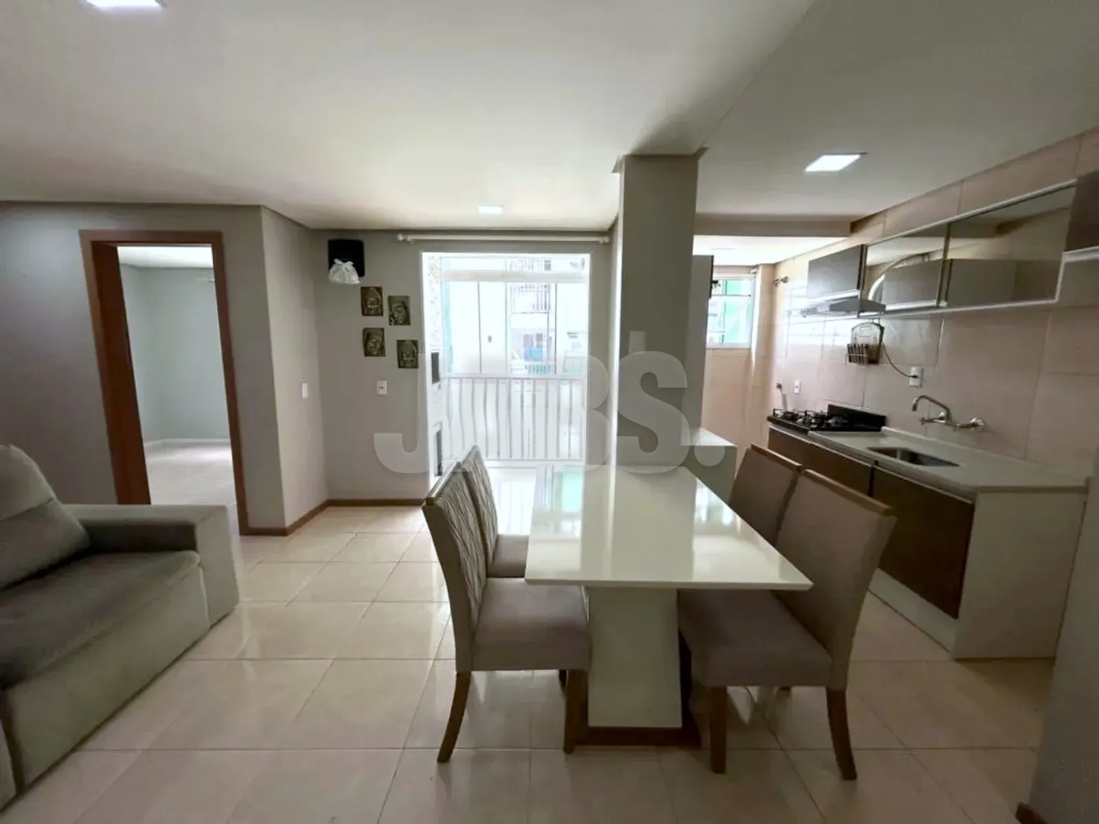 Sala integrada à cozinha, com mesa de jantar e porta para a sacada ao fundo