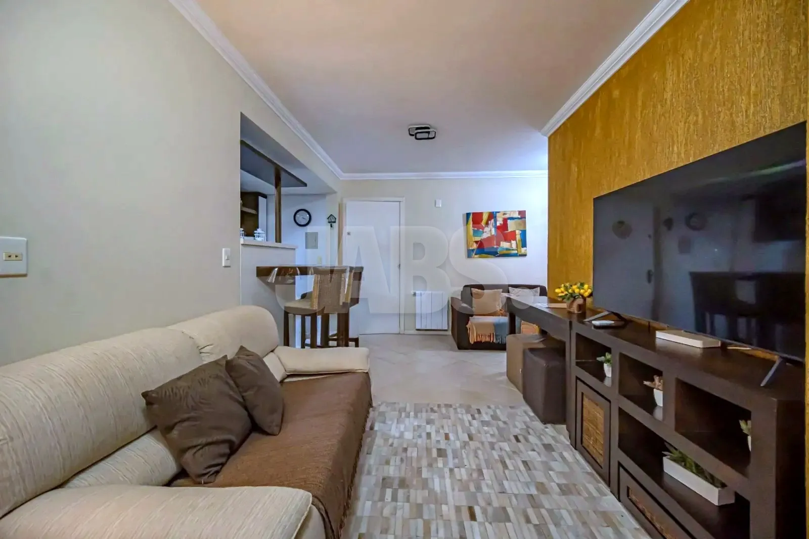 Sala vista da janela, com sofá, estante da TV e mesa ao fundo