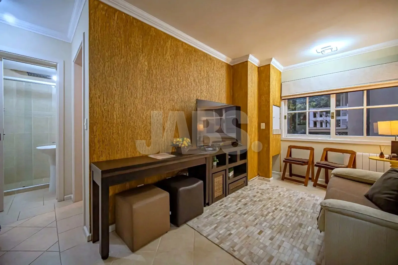 Sala com estante de madeira, pufes e cadeiras junto à janela