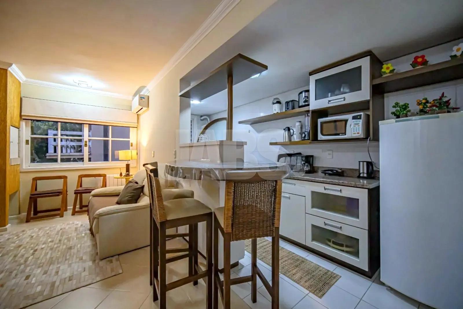 Cozinha americana com balcão, banquetas, micro-ondas e geladeira