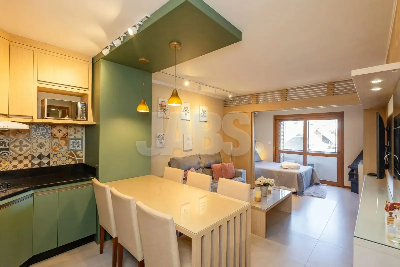 Mesa de jantar ao lado da cozinha verde com azulejos decorados e vista para o estar