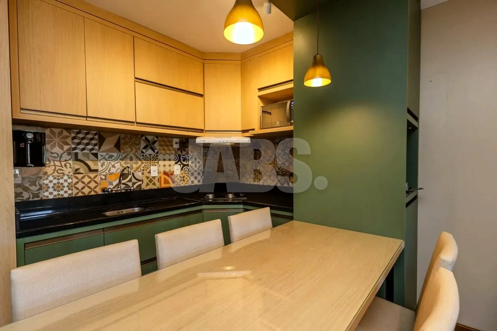 Cozinha planejada com cooktop, coifa e mesa de jantar para seis lugares