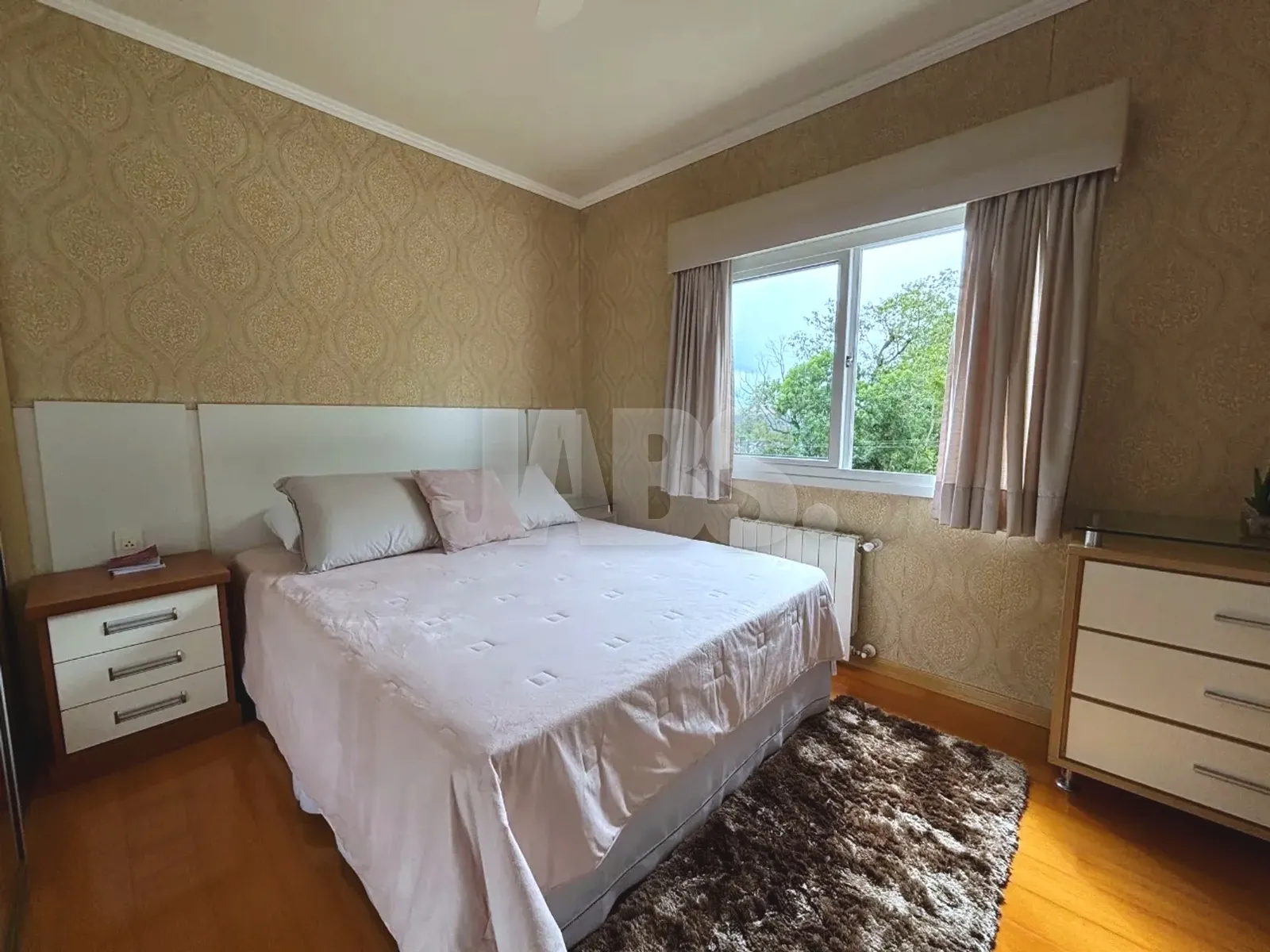 Suíte com cama de casal e janela para as árvores
