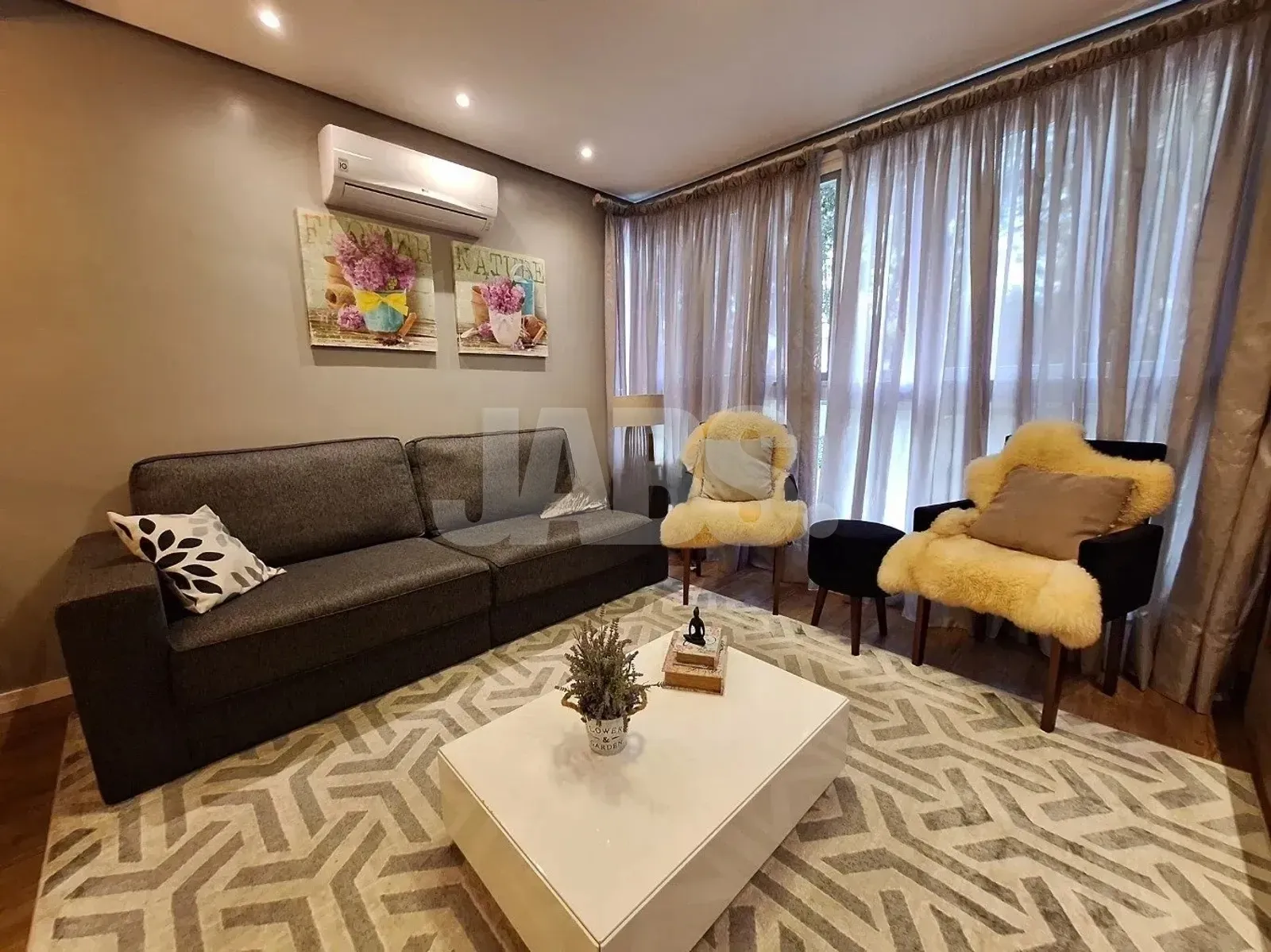 Sala com sofá, poltronas e janelas amplas