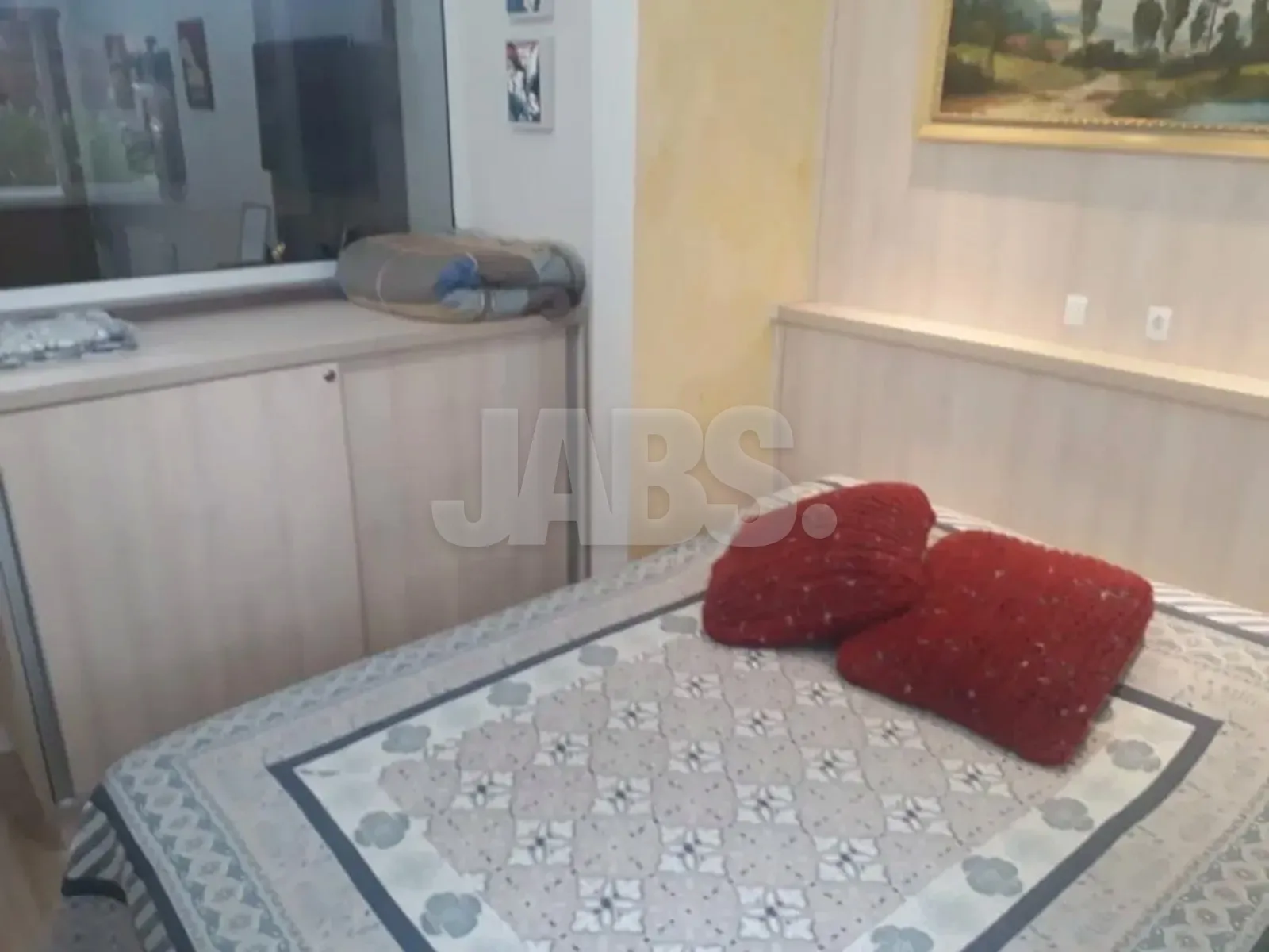 Cama de casal com colcha estampada e armário baixo de madeira clara