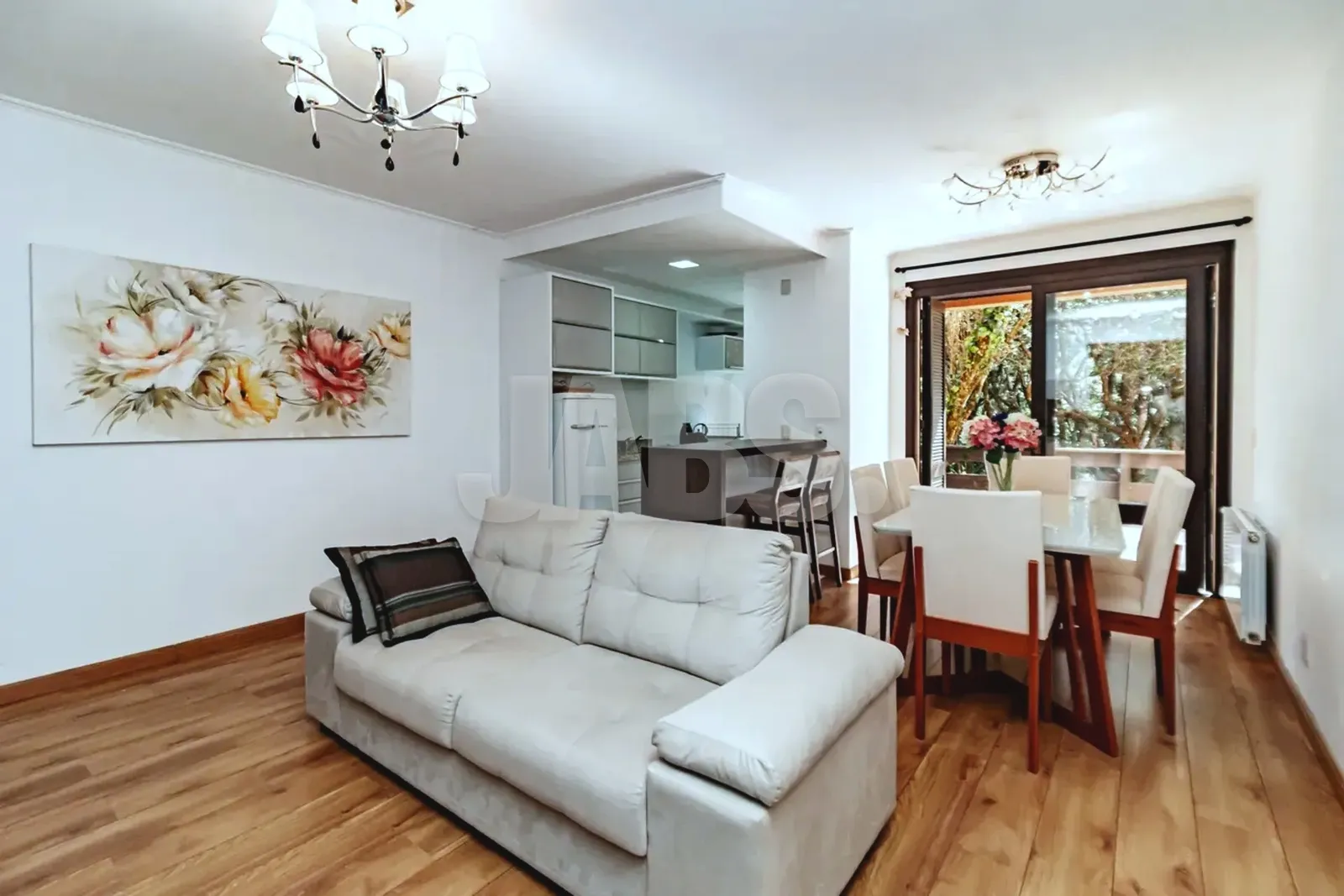 Sala de estar e jantar integradas, mobiliadas, com janela para a mata