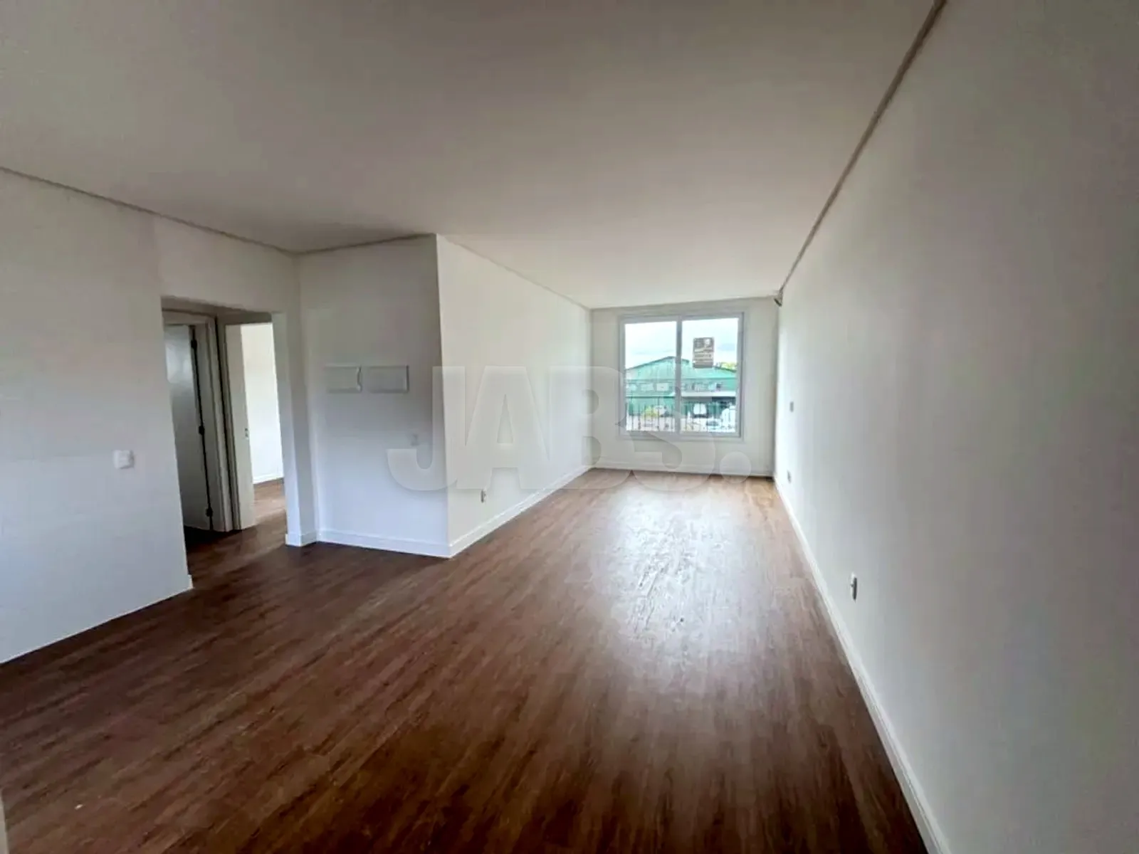 Sala ampla com piso vinílico escuro, paredes brancas e janela ao fundo