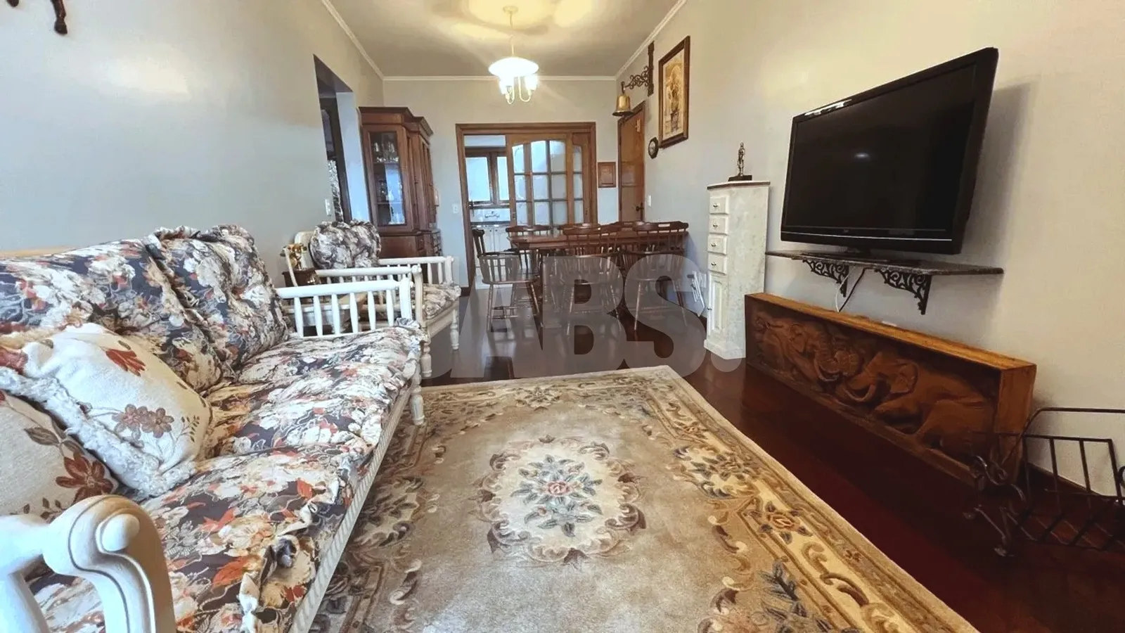 Living com sofá, tapete e sala de jantar ao fundo