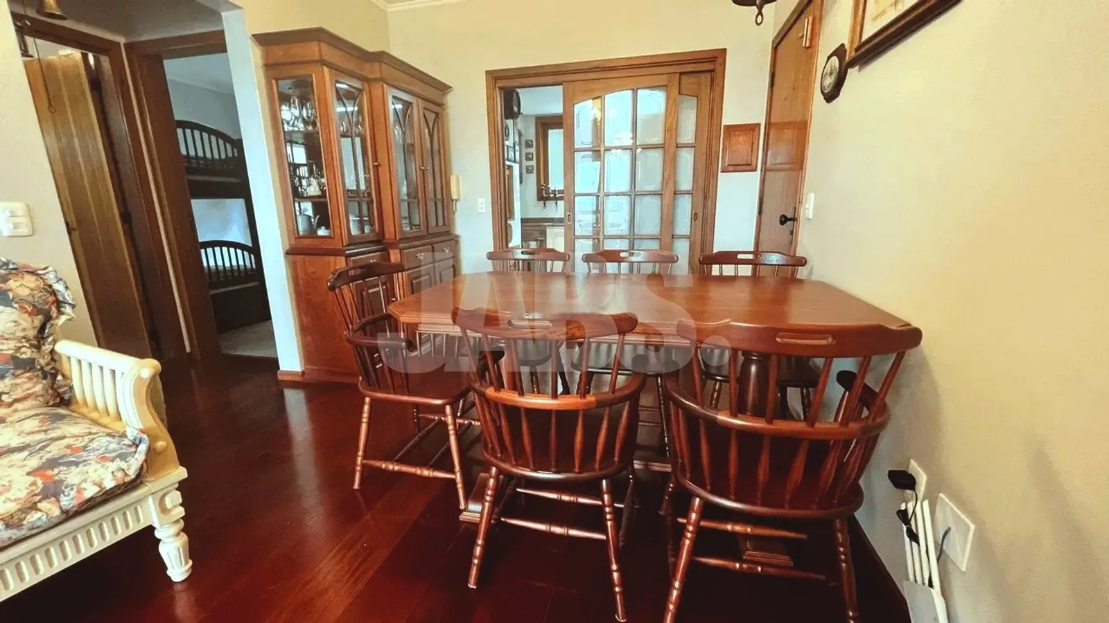 Sala de jantar com mesa de madeira e cristaleira