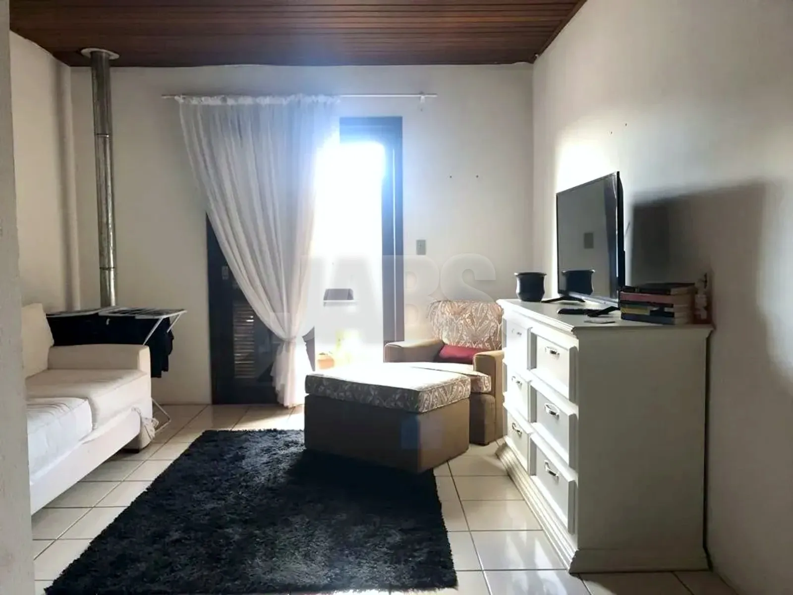 Sala de estar com sofá, tapete e porta de vidro com cortina