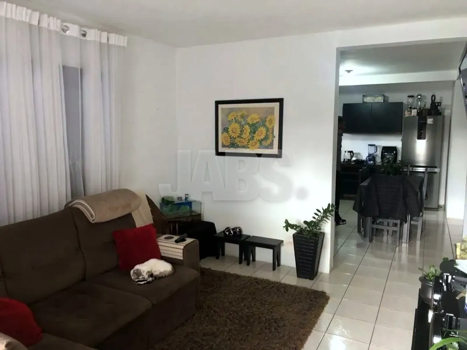 Sala com sofá marrom e passagem para a cozinha