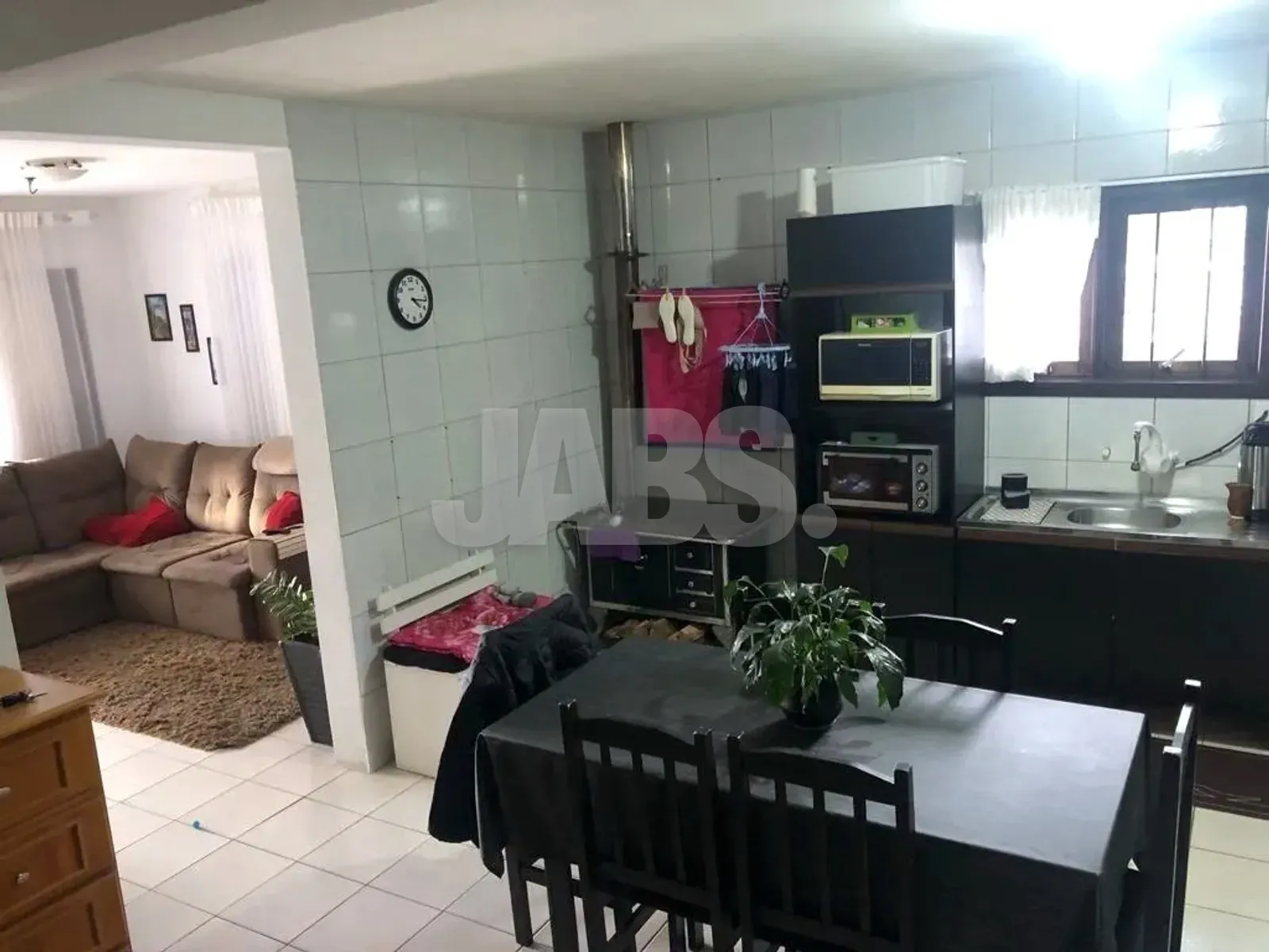 Cozinha integrada à sala de jantar, com armários escuros e mesa