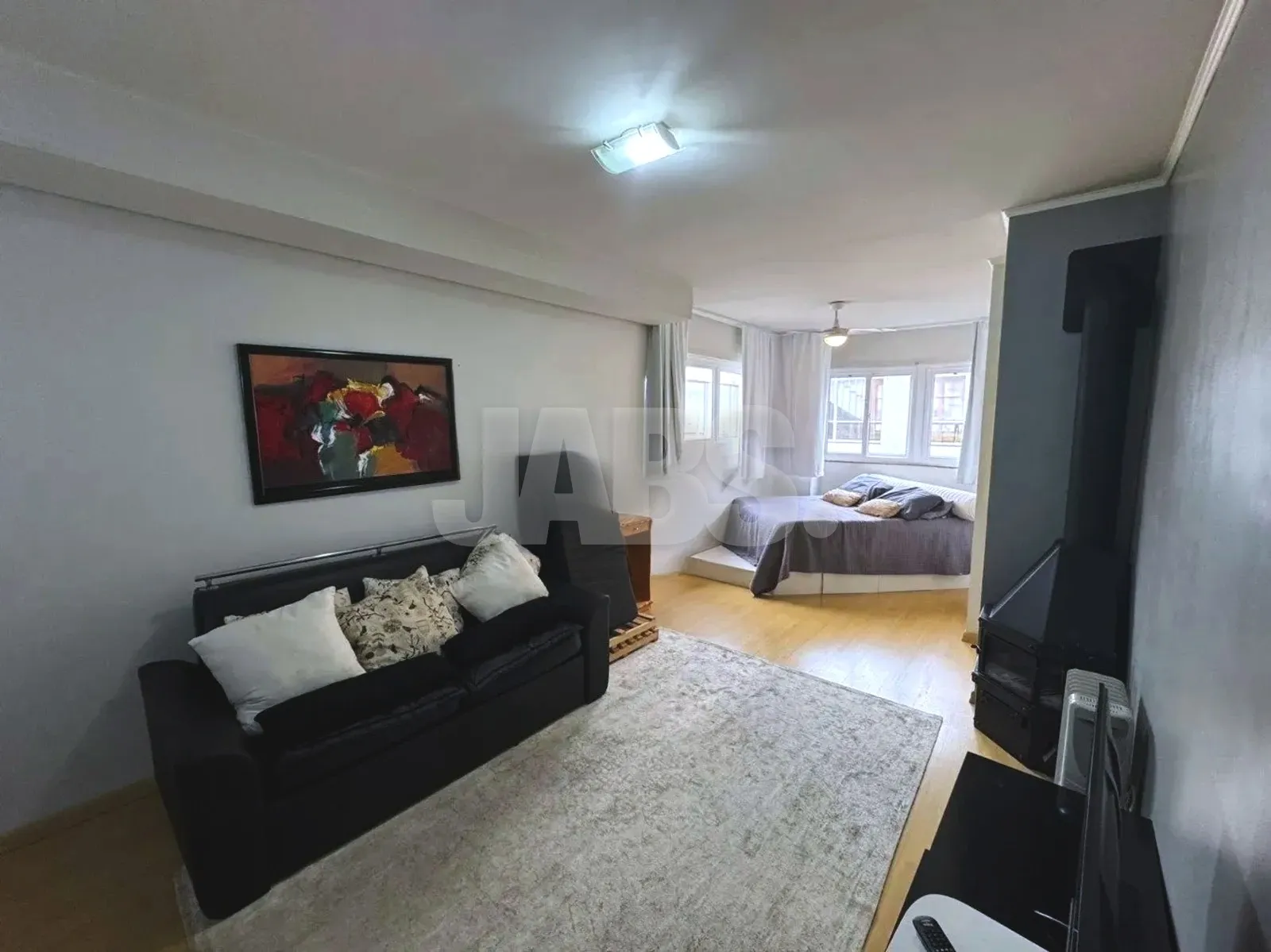 Ambiente principal com sofá, tapete e cama ao fundo