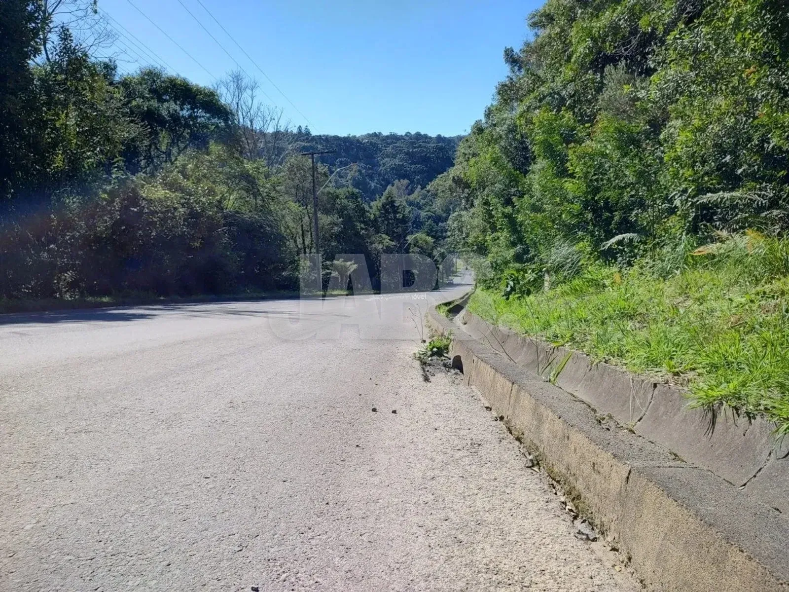 Acesso pavimentado com vista para os morros ao fundo