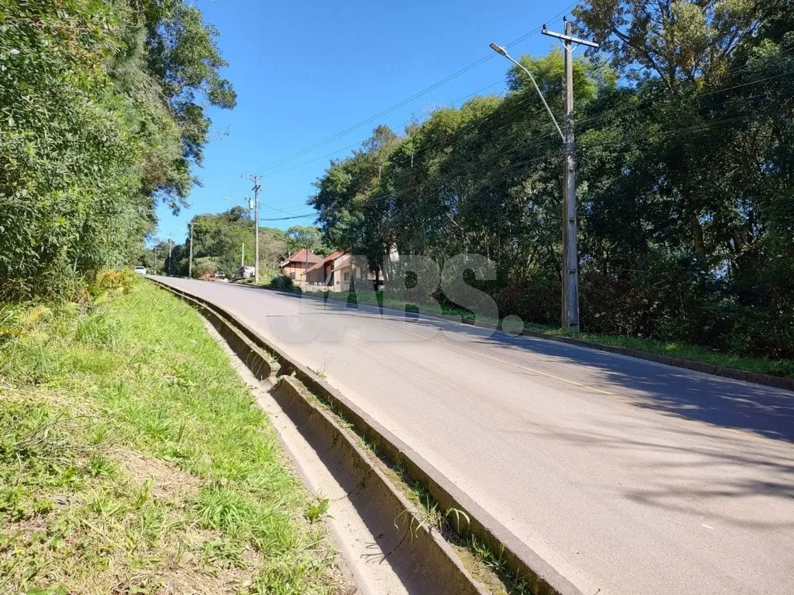 Rua do bairro com postes de luz e casas ao fundo