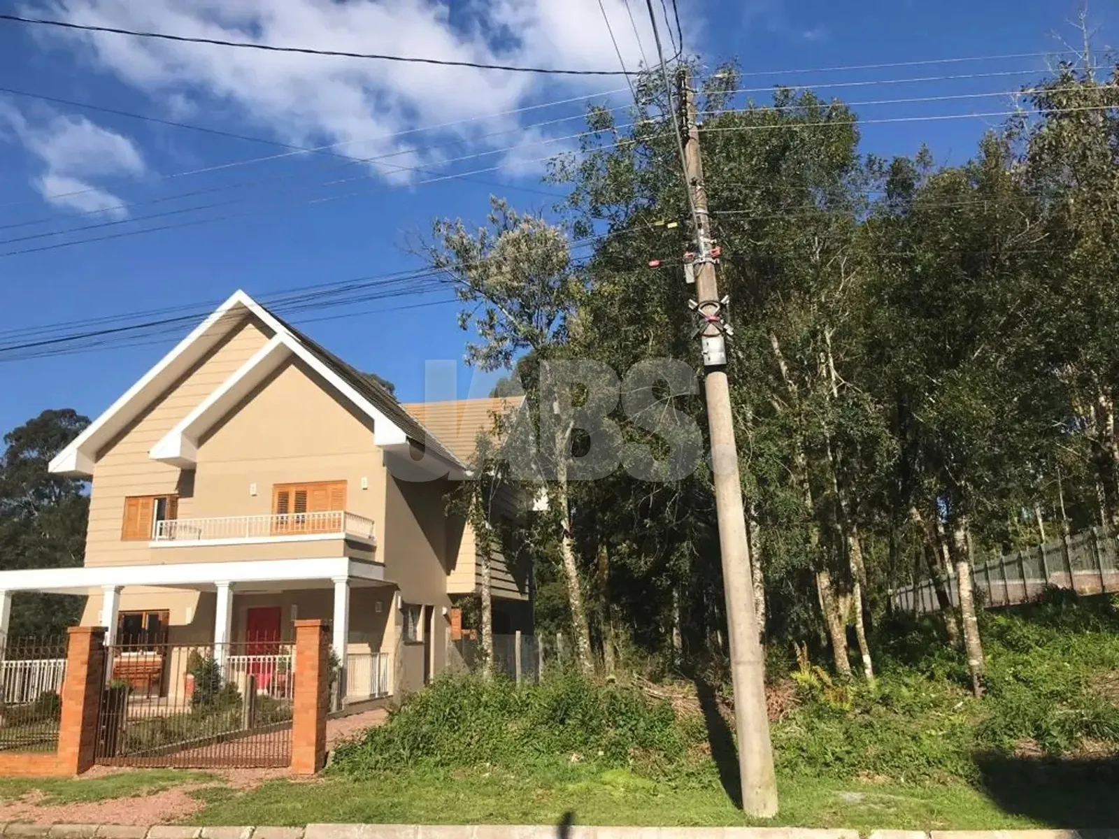 Terreno arborizado ao lado de casa em estilo serrano