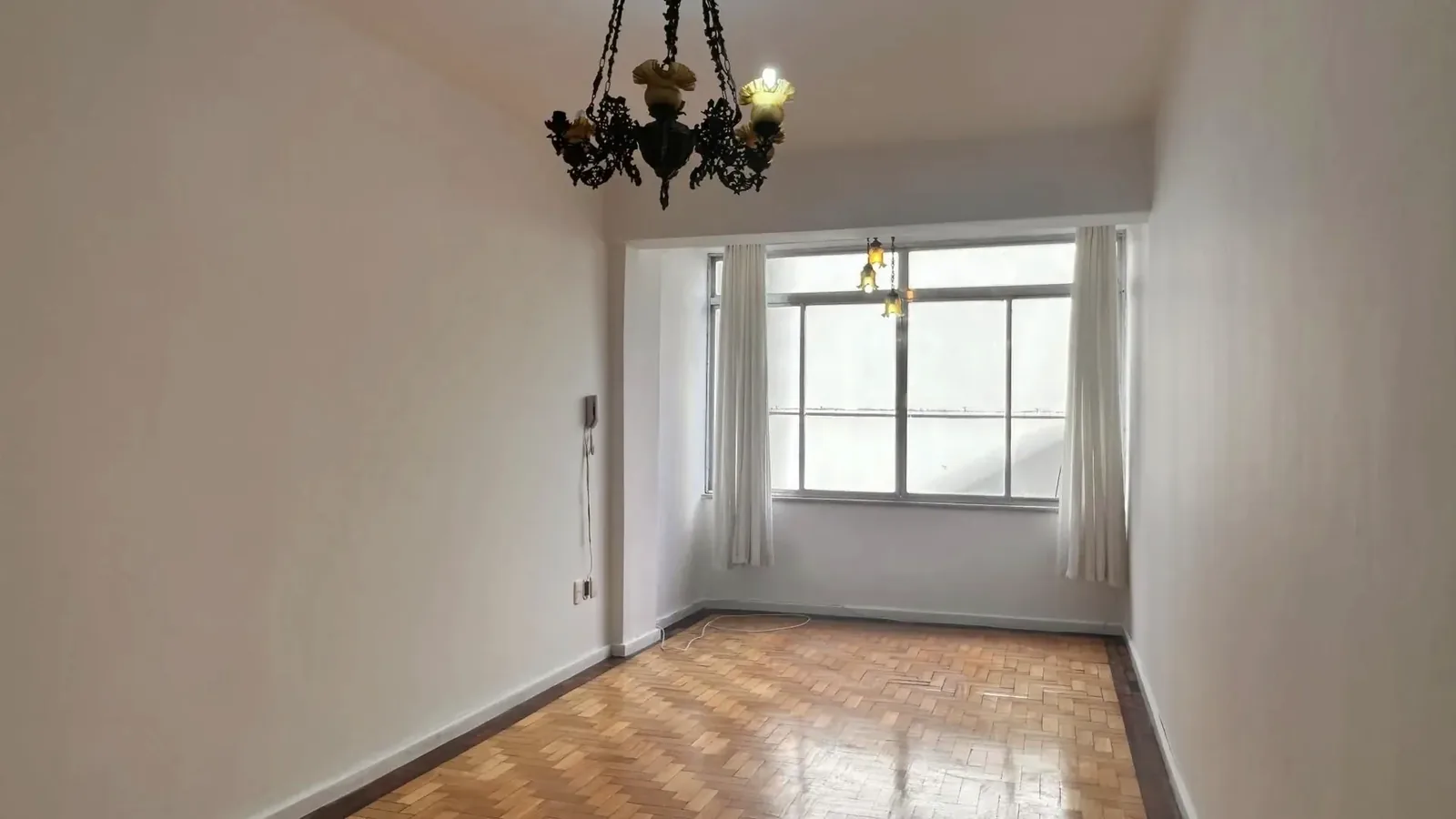 Living com piso de parquê e janela ampla na Auxiliadora, em Porto Alegre