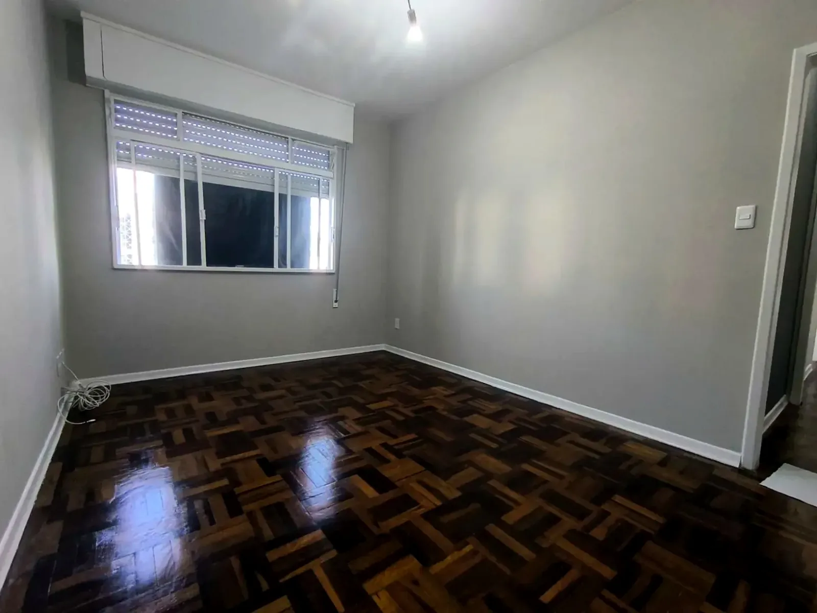 Living com piso de parquê e janela de frente