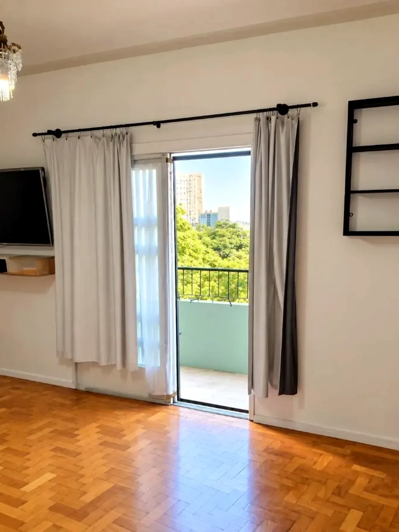 Living com piso de parquê e porta para a sacada, na Cidade Baixa