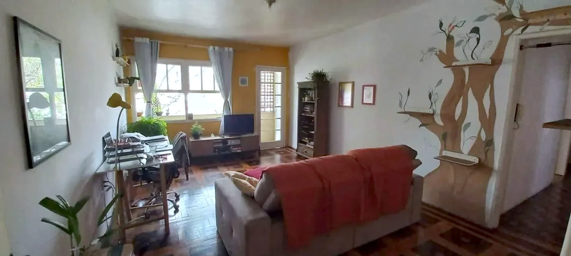 Living amplo com piso de parquet e janelas grandes