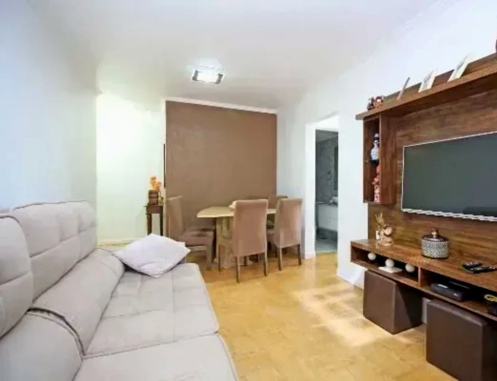 Living com sofá e painel de TV no Vivenda dos Trevos
