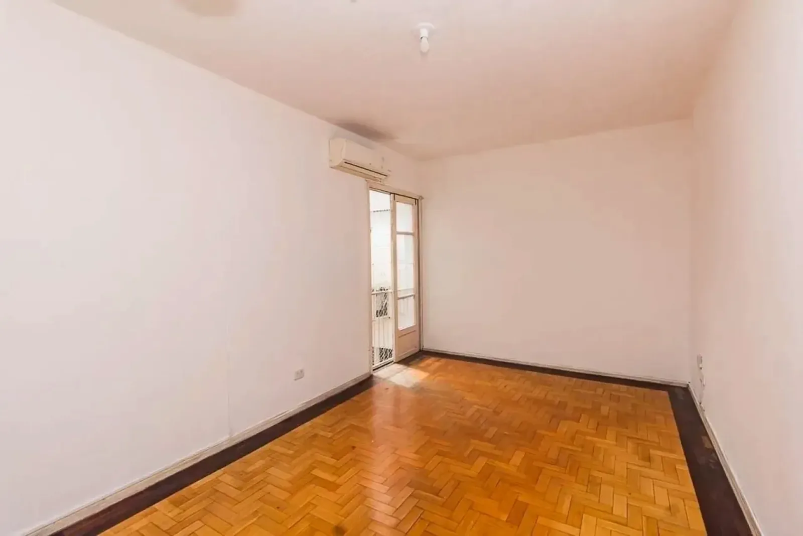 Living com piso de parquet e porta para a sacada