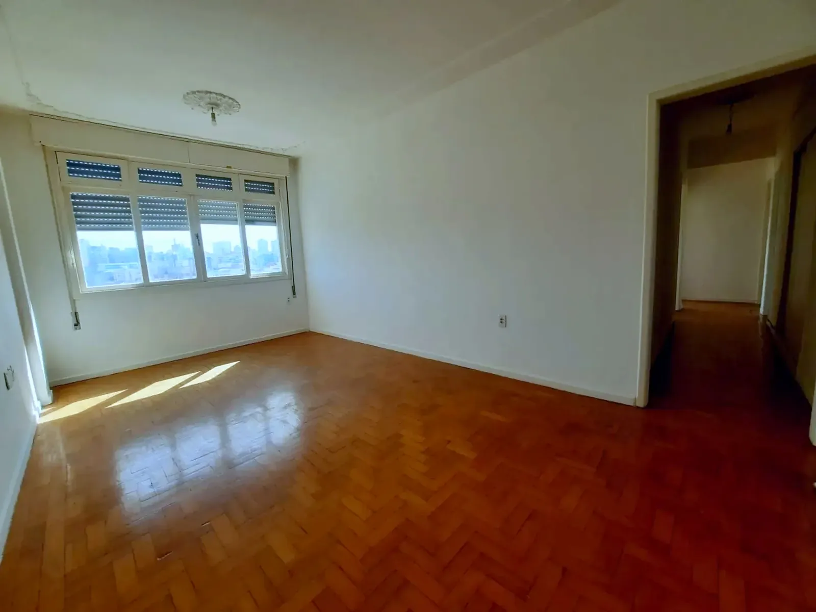 Living amplo com piso de parquê e sol da manhã