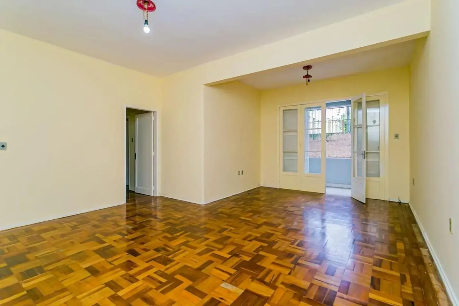 Living com piso de parquet e porta para a sacada