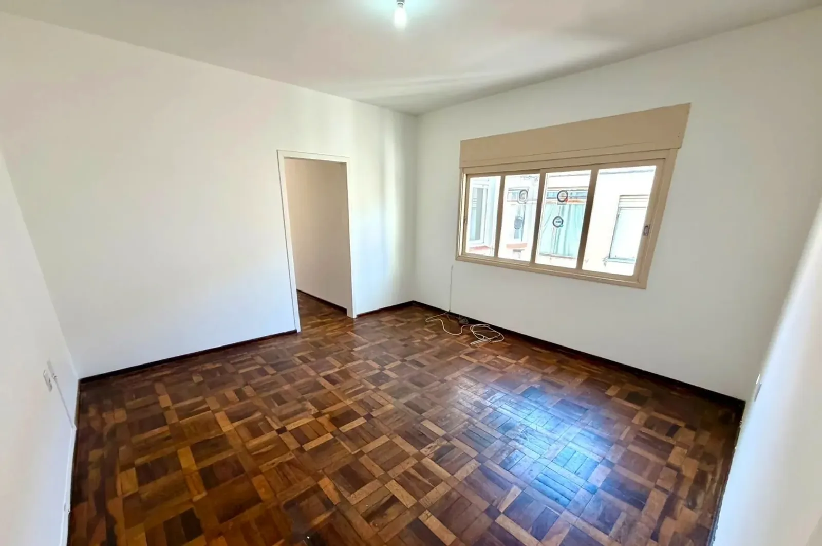 Sala com piso de parquet e janela ampla no Petrópolis