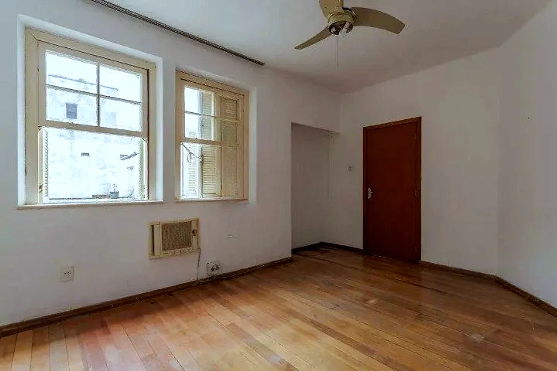 Living com piso de tabuão e janelas amplas