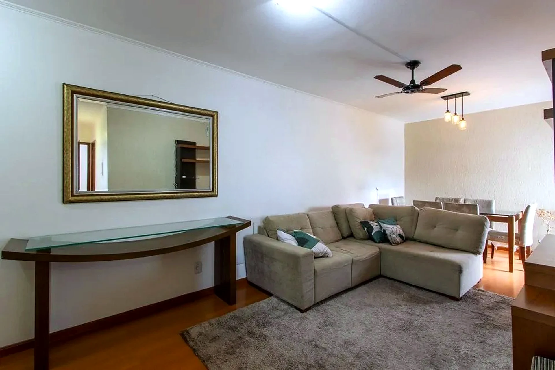 Living com espelho e piso laminado
