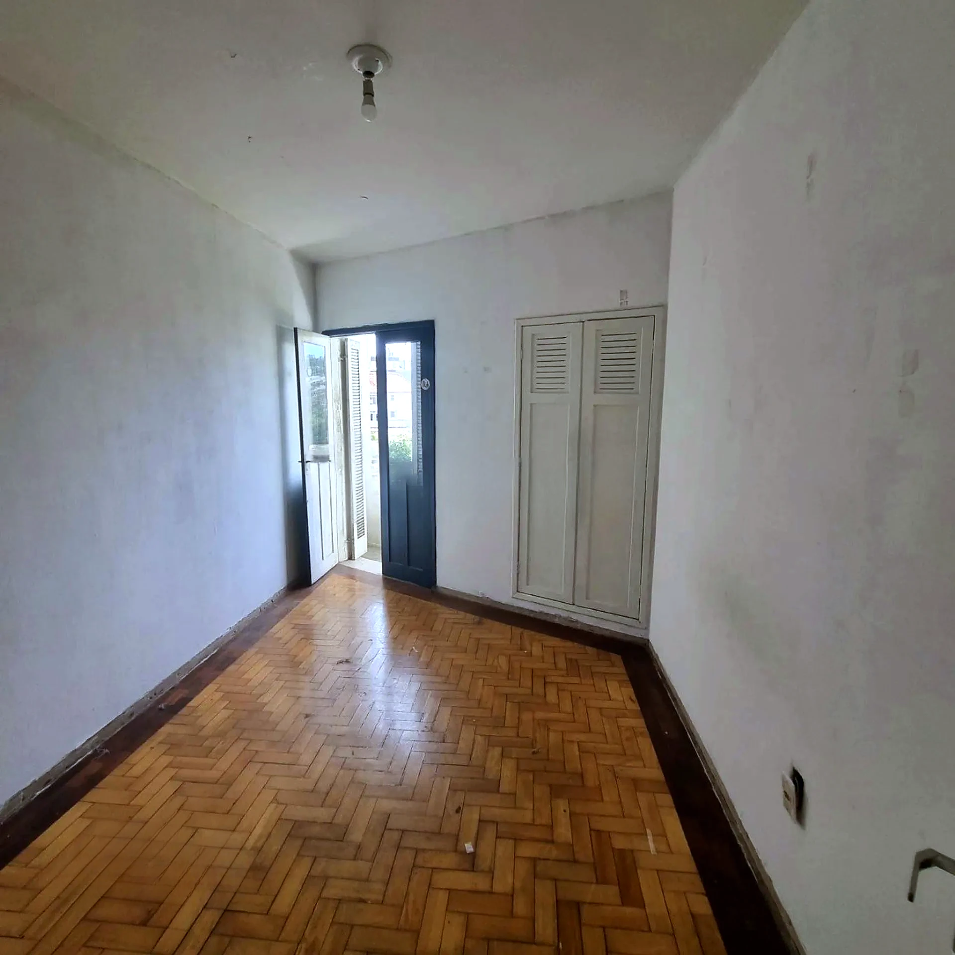 Sala com piso de parquet e porta para a sacada
