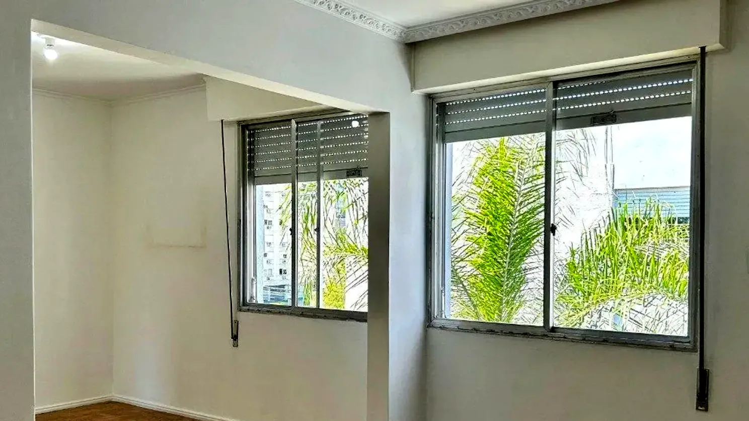 Living do apartamento com janelas largas e piso de parquê, no Menino Deus