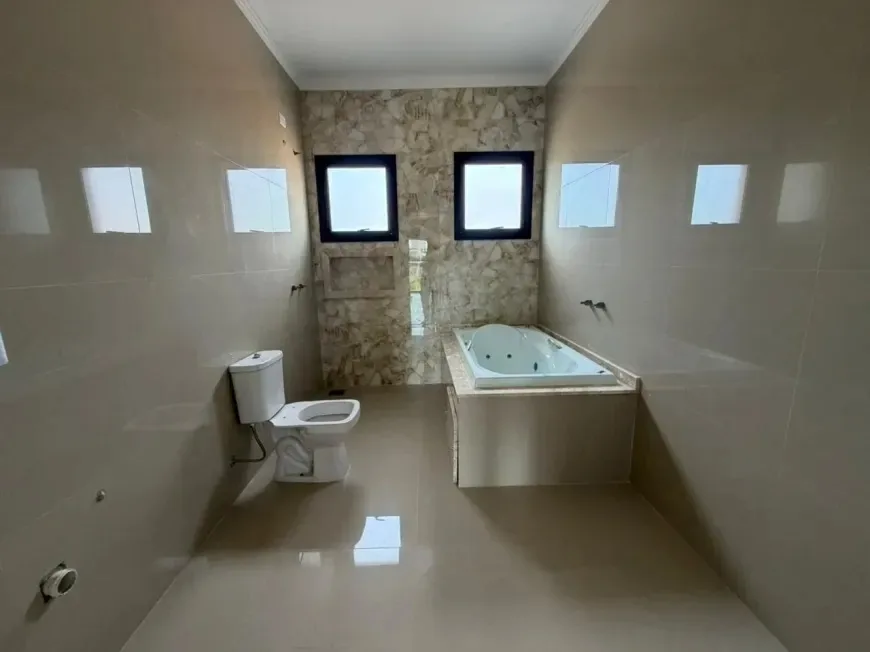 Banheiro da suíte com banheira de hidromassagem e revestimento em pedra ocre